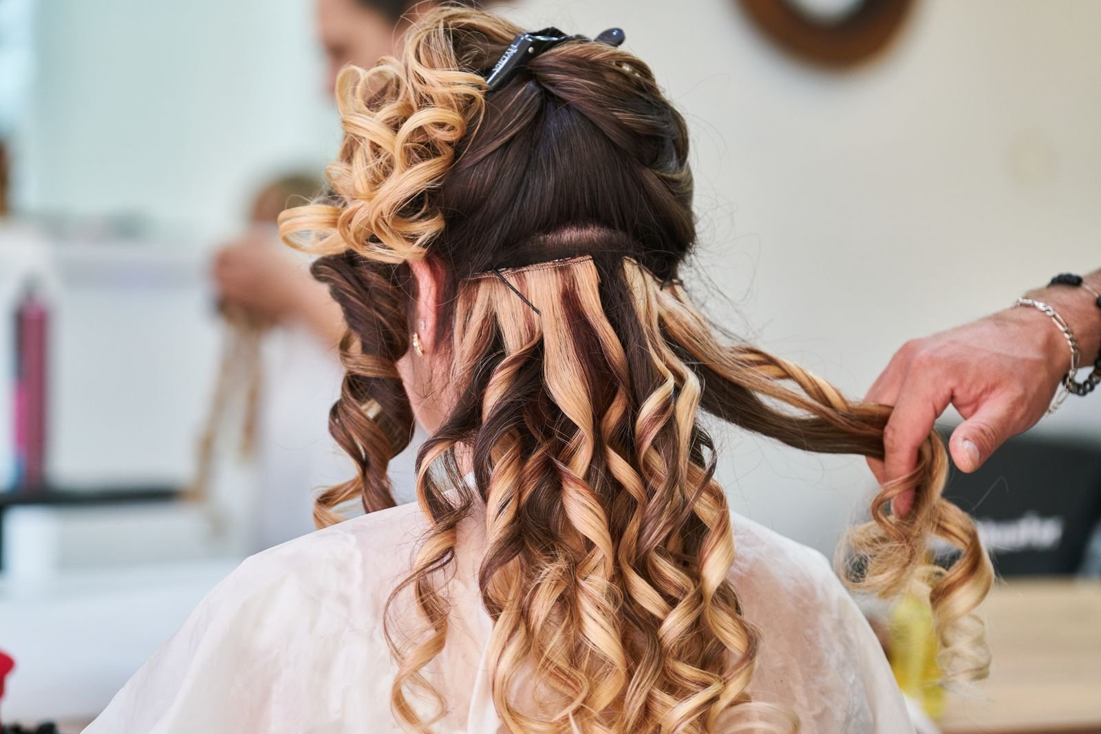 Stylist brengt tape-in hairextensions aan in de salon